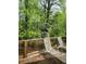 Inviting back deck with two lounge chairs and a table surrounded by lush greenery and trees at 3875 Wintergreen Ct, Marietta, GA 30062