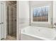 Relaxing bathroom features a soaking tub, glass-enclosed shower, and a window overlooking the backyard at 814 Harmony Rd, Temple, GA 30179