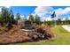 Charming community entrance sign with stone accents, landscaping, and flags against a blue sky at 165 Aster Avenue, Locust Grove, GA 30248