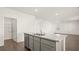 Kitchen island boasts granite countertops and stainless steel sink; door to pantry on the left at 165 Aster Avenue, Locust Grove, GA 30248