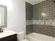 Well-lit bathroom featuring a vanity and bathtub with gray subway tile, accented by a decorative mosaic border at 554 Samaritan Dr, Cumming, GA 30040