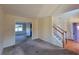 Spacious living room with staircase, carpeted floor, view into the dining area, and natural light at 7402 Gossamer St, Union City, GA 30291