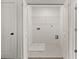 Bright laundry closet with white marble tile, wire shelving, and connections for a washer and dryer at 170 Chandler Trace, Covington, GA 30016