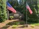 Charming community entrance featuring an attractive stone wall, beautiful landscaping, and patriotic American flags at 320 Red Fox Dr, Canton, GA 30114