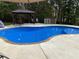 Inviting backyard pool with a surrounding patio, complemented by a shaded gazebo and green trees at 320 Red Fox Dr, Canton, GA 30114