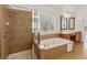 Bathroom features a tiled shower and soaking tub beneath plantation shutters at 3690 Millwater Xing, Dacula, GA 30019