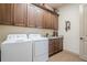 Functional laundry room featuring granite countertops, wood cabinets, and modern appliances at 4880 Cecilia Sq, Cumming, GA 30040