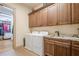 Well-equipped laundry room with granite countertops, custom wood cabinets, and modern washer and dryer at 4880 Cecilia Sq, Cumming, GA 30040