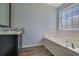 Bathroom featuring a bathtub, dark vanity with backsplash and hardwood floors at 420 Sanford Creek Ln, Lawrenceville, GA 30045