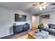 Living room featuring a large TV, gray sectional sofa, ceiling fan, wooden coffee table, and hardwood floors at 845 Connell Ln, Lawrenceville, GA 30044