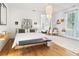 Bright bedroom with hardwood floors, white walls, a white bed, a large chandelier, and a sitting room area at 565 Candler St, Atlanta, GA 30307