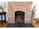 Close-up of the brick fireplace with decorative tile and hearth, accented by vintage decor and hardwood floors at 565 Candler St, Atlanta, GA 30307