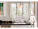 Bright kitchen featuring black tiled countertops, white cabinetry, a vintage light, and natural light from three large windows at 565 Candler St, Atlanta, GA 30307