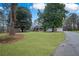 Expansive lawn with mature trees framing a well-maintained home with a welcoming front porch at 2820 Maxwell Pl, Lithia Springs, GA 30122