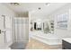 Bright bathroom featuring a garden tub with tile surround and large window to bring in natural light at 4805 Mystere Sw Ln, Lilburn, GA 30047