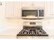 Close-up of a modern stainless steel gas stovetop with white countertops and cabinets at 244 Amelia Garden Way, Lawrenceville, GA 30045