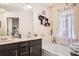 Bright bathroom featuring a double vanity, soaking tub, decorative shelving, and a window with elegant curtains at 3362 Brockenhurst Dr, Buford, GA 30519