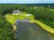 Aerial view of a house with a pond and a basketball court nestled in lush green trees at 535 Waters Way, Fayetteville, GA 30215