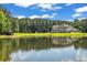 A picturesque pond reflecting the home and sky, surrounded by mature trees at 535 Waters Way, Fayetteville, GA 30215