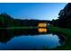 Reflective pond mirroring a grand estate with a lush, green lawn and bordering trees at 535 Waters Way, Fayetteville, GA 30215