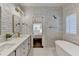 Bathroom featuring white cabinets and subway tiles, double sinks and a bathtub near the window at 3355 Olivia Ct, Cumming, GA 30041