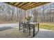 Covered back patio with outdoor dining, overlooks gravel parking, and wooded area at 115 Bruce Rd, Douglasville, GA 30134