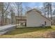 View of the side of the house with a deck, concrete patio, and gravel driveway surrounded by leafless trees at 115 Bruce Rd, Douglasville, GA 30134