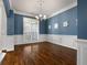 Dining room featuring hardwood floors, blue walls with white wainscoting, and an elegant chandelier at 155 Rose Creek Dr, Covington, GA 30014