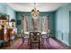 Formal dining room with blue walls, chandelier, wood table, and chairs, complemented by elegant decor at 9465 Mistwater Close, Roswell, GA 30076