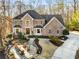 Stately brick home featuring a landscaped yard, outdoor firepit, and a circular driveway surrounded by mature trees at 9465 Mistwater Close, Roswell, GA 30076