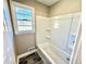 Bathroom with a white tiled tub, window, and modern fixtures at 1091 Mountain View Nw Rd, Conyers, GA 30012