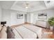 Virtually staged main bedroom with a tray ceiling, ceiling fan, and an ensuite bathroom entrance, with hardwood floors at 4565 Bridle Point Pkwy, Snellville, GA 30039