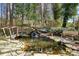 Scenic backyard pond featuring a charming wooden bridge and stone accents, surrounded by lush greenery at 203 Northside Nw Dr, Kennesaw, GA 30144
