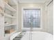 Close up of soaking tub with patterned window, glass shower, and custom shelving at 1884 Point River Dr, Duluth, GA 30097