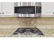 Kitchen area featuring stainless steel gas cooktop, microwave, and decorative backsplash at 1884 Point River Dr, Duluth, GA 30097