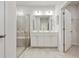 Well-lit bathroom with a glass-enclosed shower, double vanity, white cabinetry, and tile flooring at 3891 Shelleydale Dr, Powder Springs, GA 30127