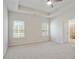 Airy primary bedroom features a tray ceiling, cozy carpeting, and natural light from two windows at 3891 Shelleydale Dr, Powder Springs, GA 30127