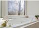 Close up shot of bathroom soaking tub with decorative glass window above at 7455 Richmond Way, Cumming, GA 30040