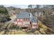 Rear exterior view of the brick home, with a deck accessible via stairs, surrounded by lush greenery at 7455 Richmond Way, Cumming, GA 30040