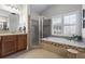 Bright bathroom featuring a soaking tub, a glass shower, and a vanity with wood cabinets at 2061 Westwood Cir, Smyrna, GA 30080