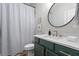 Bathroom with green vanity, marble countertop, modern gold faucet and black and white striped shower curtain at 2061 Westwood Cir, Smyrna, GA 30080