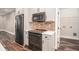 Kitchen featuring white cabinets, stainless steel appliances, brick backsplash, and access to a laundry room at 210 Joe Green Ln, Canton, GA 30114