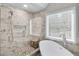 Bright bathroom with a soaking tub next to the glass enclosed shower with white and grey tile surround at 4000 Rockingham Dr, Roswell, GA 30075