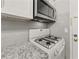 Close-up on stove and microwave above white kitchen cabinets with granite countertops at 6851 Roswell Rd # F32, Sandy Springs, GA 30328