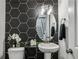 Chic powder room features hexagon tile backsplash, pedestal sink, oval mirror, and modern fixtures, adding stylish functionality at 1322 Stanley Park Dr, Decatur, GA 30033