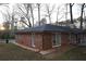 Back exterior of the house with brick and large windows surrounded by trees at 4765 Fellswood Dr, Stone Mountain, GA 30083