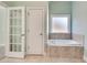 A bathroom with a corner tub, tile floor and double doors at 2477 Misty Rose Ln, Loganville, GA 30052