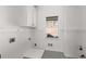 Clean laundry room with white wainscoting, patterned tile floor, and natural light from the window at 2885 Towne Village Dr, Duluth, GA 30097