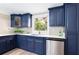 This kitchen features navy blue cabinets with gold hardware, stainless steel dishwasher, and views of the backyard at 1416 Mcpherson Se Ave, Atlanta, GA 30316