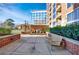 Brick patio with a seating area and green hedges in front of a condominium building at 1820 Peachtree Nw St # 1207, Atlanta, GA 30309